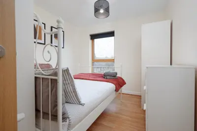 a white bedroom with a bunk bed and a window at 2BR Apartment with Parking Near Southside and Queens Park in Mansewood