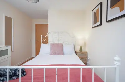 a bedroom with a white bed with a pink pillow at 2BR Apartment with Parking Near Southside and Queens Park in Mansewood