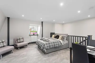 a bedroom with a bed and two chairs at Large Edinburgh Studio - Close to City Centre, Murrayfield and Airport in Edinburgh
