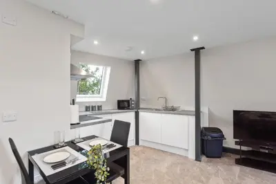 a kitchen and dining room with a table and a television at Large Edinburgh Studio - Close to City Centre, Murrayfield and Airport in Edinburgh
