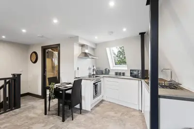 a kitchen with white cabinets and a table and a dining room at Large Edinburgh Studio - Close to City Centre, Murrayfield and Airport in Edinburgh
