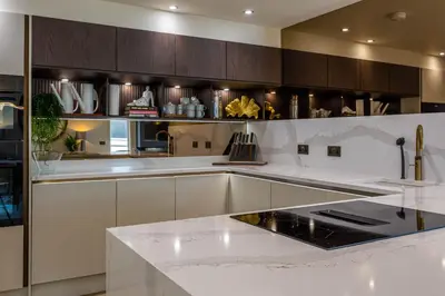 a kitchen with white counters and wooden cabinets at The Shore House in Lamlash