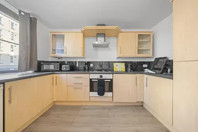 a kitchen with wooden cabinets and a stove top oven at Lauriston 1 Bedroom Apartment - Edinburgh in Edinburgh