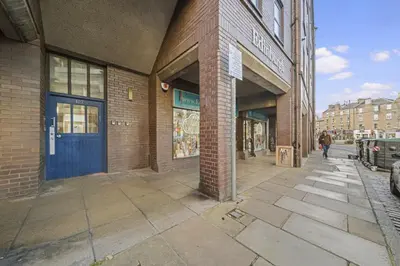 a brick building with a blue door on a street at Lauriston 1 Bedroom Apartment - Edinburgh in Edinburgh