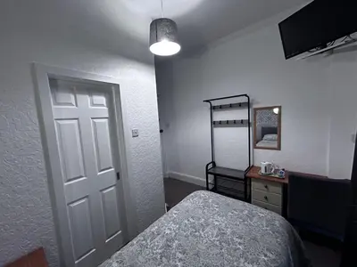 a bedroom with a bed and a mirror and a door at Glendale Guesthouse in Oban