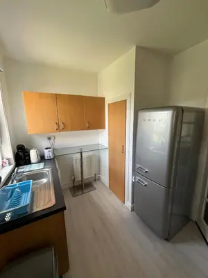 a kitchen with a stainless steel refrigerator and wooden cabinets at Glasgow 2 Bedroom Apartment Access To City Centre in Gartcosh