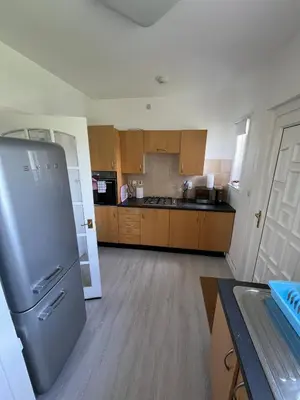 a kitchen with a stainless steel refrigerator and wooden cabinets at Glasgow 2 Bedroom Apartment Access To City Centre in Gartcosh