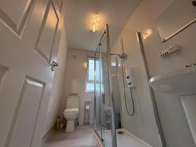 a bathroom with a shower and a toilet and a sink at Glasgow 2 Bedroom Apartment Access To City Centre in Gartcosh