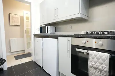 a kitchen with white cabinets and a black and white dishwasher at Stobhill Apartment in Glasgow
