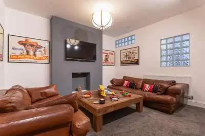 a living room with brown leather couches and a table at Faulkner Luxury Suites in Moffat