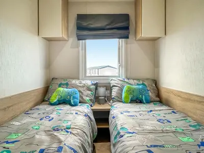 a small bedroom with two beds and a window at Coastal Bay View in Ayr