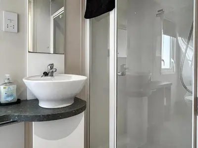 a white bathroom with a sink and a shower at Coastal Bay View in Ayr