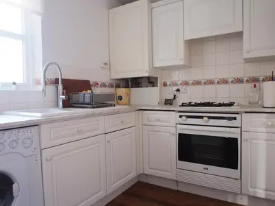 a kitchen with white cabinets and a stove top oven at Fettes - Homely 2BD in Quiet Development in Edinburgh