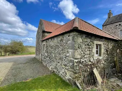 an old stone building with a bench next to a road at Linlithgow cottage close to Edinburgh in Linlithgow