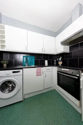 a kitchen with white cabinets and a washer and dryer at Stylish and Unique Apartment by the Meadows 8 in Edinburgh