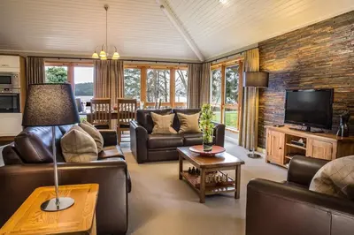 a living room with leather furniture and a tv at 2 Bedroom detached lodge overlooking Loch Lomond in Balloch