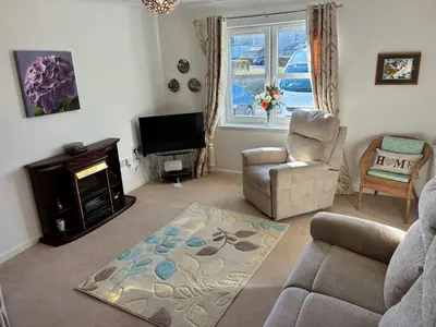 a living room with a couch and a chair and a television at Westcoast-Retreat-Largs in Largs