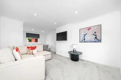 a white living room with a white couch and a table at The Elphin Escape in East Kilbride