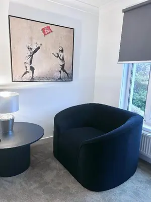 a living room with a blue chair and a table at The Elphin Escape in East Kilbride