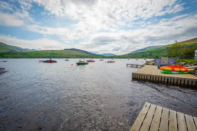 a group of boats on a lake with mountains at The Clachan Hotel, Lochearnhead in Lochearnhead