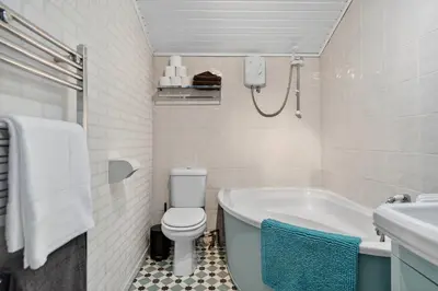 a bathroom with a tub and a toilet and a sink at Coastal Charm: Modern Retreat by Seafront in Largs