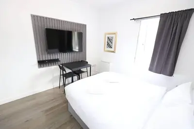 a bedroom with a bed and a desk with a television at Glasgow Studio in Glasgow
