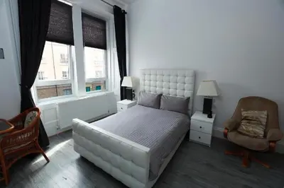 a bedroom with a large white bed and a chair at Glasgow Studio in Glasgow