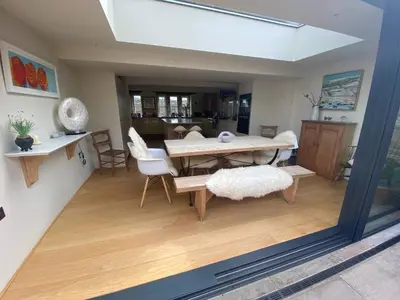 a living room with a table and a dining room at Woodlea Cottage in Moffat