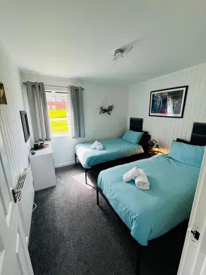 two beds in a room with blue sheets at Tigh Na Sealladh in Dunoon