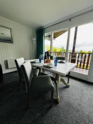 a dining room with a table and chairs and a balcony at Tigh Na Sealladh in Dunoon