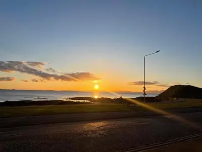 a sunset over the ocean with a street light at Seaview Retreat in Troon