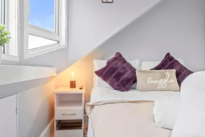 a bedroom with a bed with purple pillows and a window at Charming Village Escape 3-Bed near Loch Lomond in Drymen