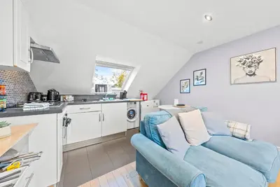a living room with a blue couch and a kitchen at Charming Village Escape 3-Bed near Loch Lomond in Drymen