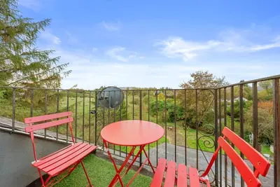 a red table and two chairs on a balcony at Charming Village Escape 3-Bed near Loch Lomond in Drymen