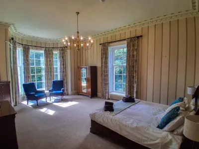 a bedroom with a bed and two chairs and a chandelier at Hillside House in Dunfermline