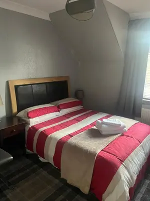 a bedroom with a large bed with red and white sheets at Rowan in Bellshill