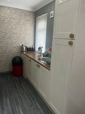 a kitchen with white cabinets and a sink at Rowan in Bellshill