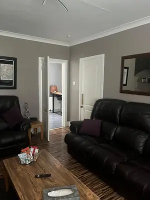 a living room with a leather couch and a table at Rowan in Bellshill