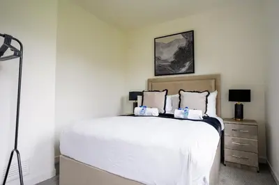 a bedroom with a large white bed and a lamp at 2 BDR Apartment By Caledonia Luxe Stays Short Lets & Serviced Accommodation Airdrie in Airdrie