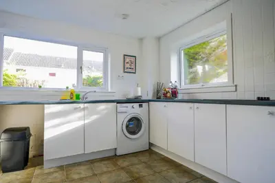 a white kitchen with a washer and dryer in it at Train House in Dunfermline