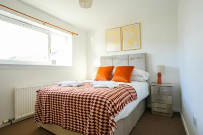a bedroom with a bed with orange pillows and a window at Train House in Dunfermline