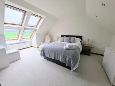 a bedroom with a large bed and two windows at Sealladh Mor-Cottage in Lamlash, Arran in Lamlash
