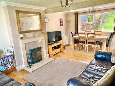 a living room with a couch and a table and a television at Four Woodside in Craighouse