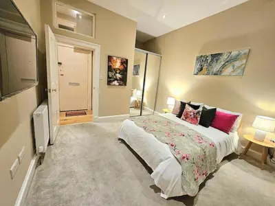 a bedroom with a large bed and a tv at 2 Bedroom Apt, 4 Beds, 3 TV near Fountain Park in Edinburgh