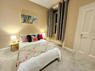 a bedroom with a large bed with flowers on it at 2 Bedroom Apt, 4 Beds, 3 TV near Fountain Park in Edinburgh