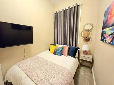 a bedroom with a bed and a flat screen tv at 2 Bedroom Apt, 4 Beds, 3 TV near Fountain Park in Edinburgh