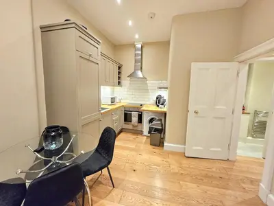 a kitchen with a glass table and black chairs at 2 Bedroom Apt, 4 Beds, 3 TV near Fountain Park in Edinburgh