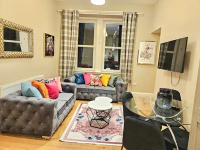 a living room with two couches and a glass table at 2 Bedroom Apt, 4 Beds, 3 TV near Fountain Park in Edinburgh