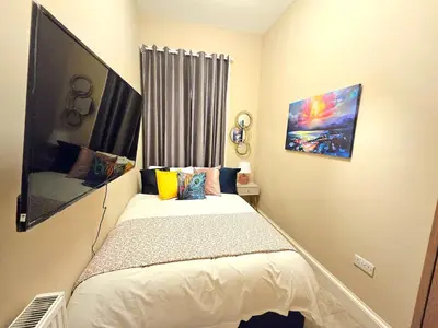 a small bedroom with a bed and a window at 2 Bedroom Apt, 4 Beds, 3 TV near Fountain Park in Edinburgh