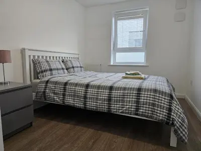 a bedroom with a bed with a plaid blanket and a window at Stylish 2-Bed Flat with Open-Plan Living plus Parking in Edinburgh